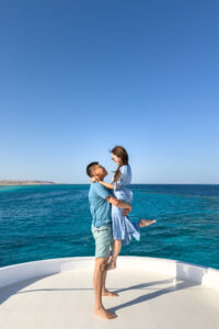 Eric lifting Kamy in the air on the deck of a boat.