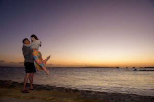 Eric lifting Kamy in the air at the shore with beautiful twilight.