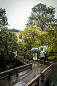 Kamy and Eric walking in a Chinese garden walkway in the rain